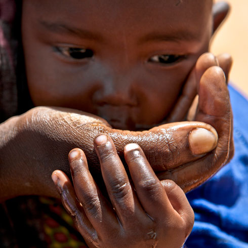 Un petit enfant boit de l'eau directement de la main.