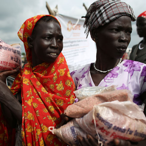 Deux femmes portent des sacs pleins de semences.