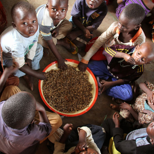 Des enfants sont assis en cercle autour d'un bol et mangent.