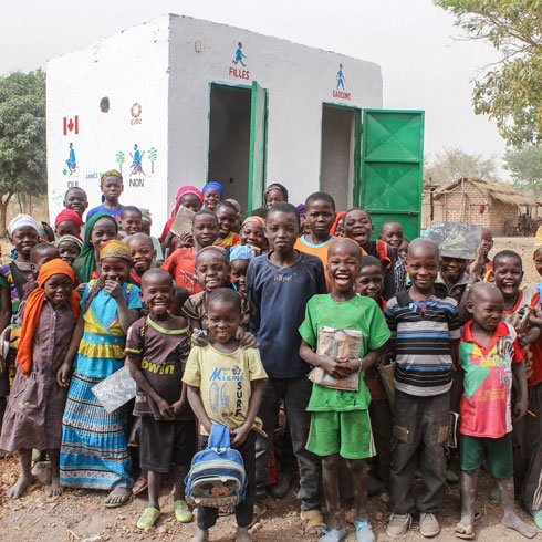 Un groupe d'enfants se tient devant des toilettes.