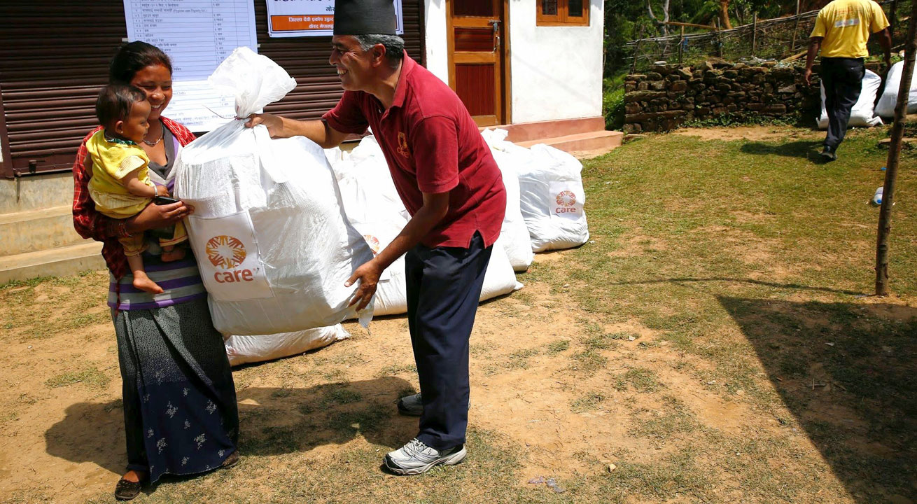 Un employé CARE donne des biens à une mère et ses enfants. Foto: CARE/Ruhani Kaur