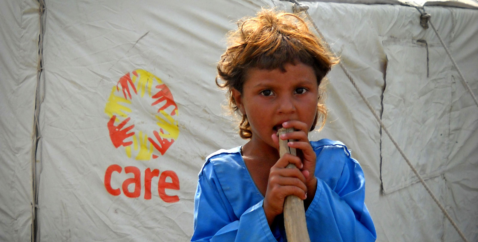 Un enfant sans abri en face de la tente du service médicale mobile de CARE.