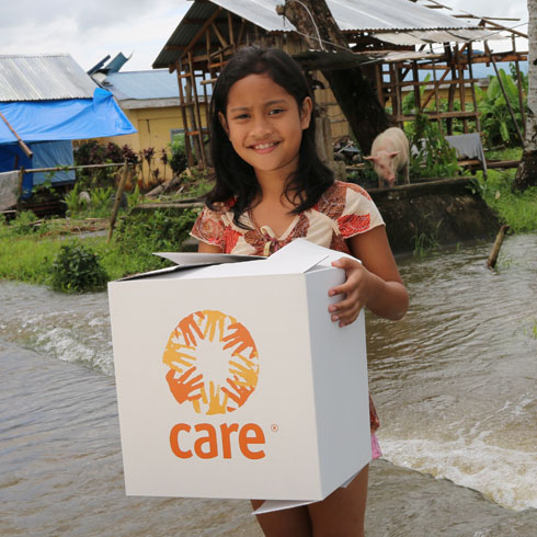 Une fille tient un colis CARE dans ses mains et sourit.